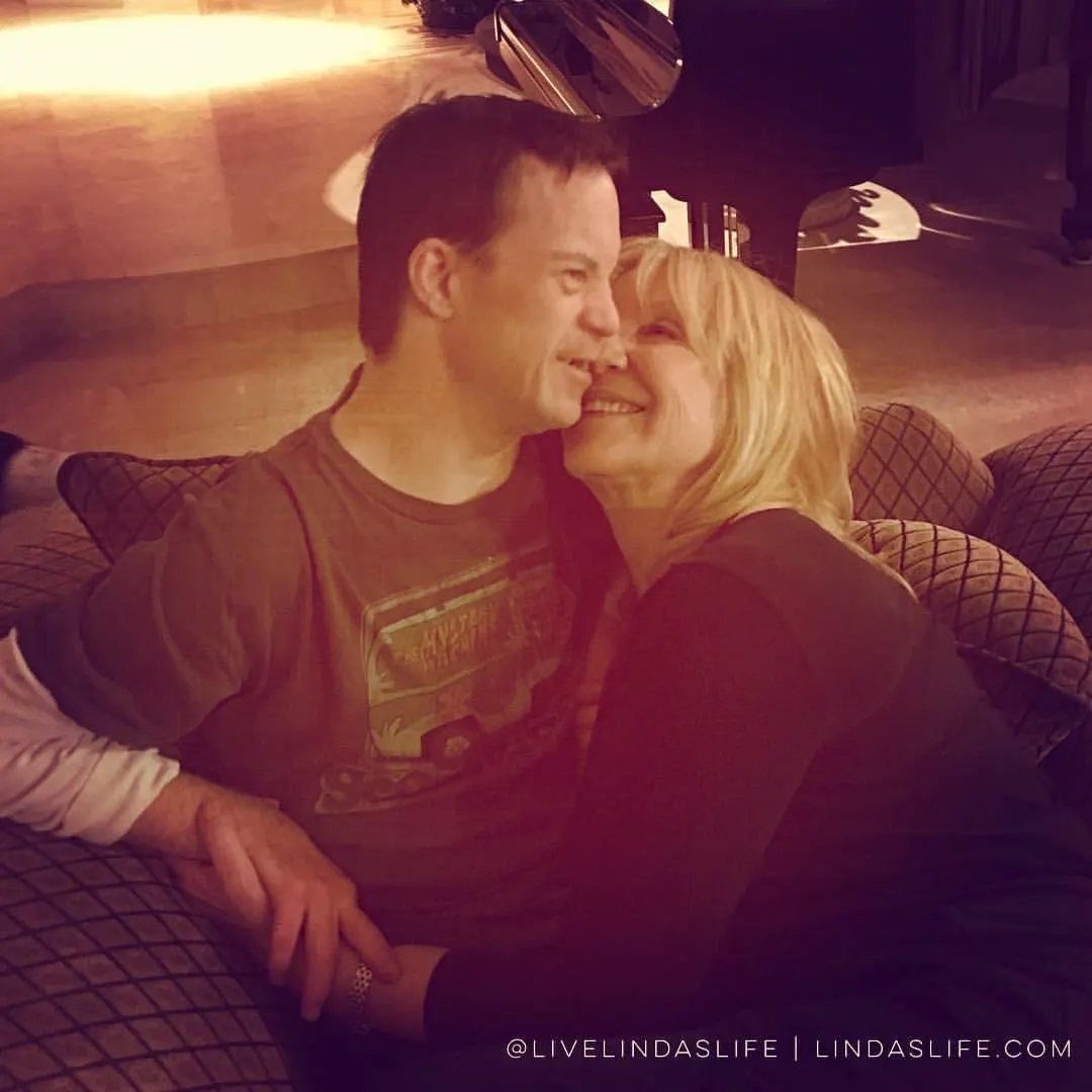 Linda Smith, a disability advocate, is joyfully embracing her son, who has Down syndrome, in a warmly lit living room, reflecting her inspirational storytelling and advocacy work.| Linda’s Life – Linda Smith