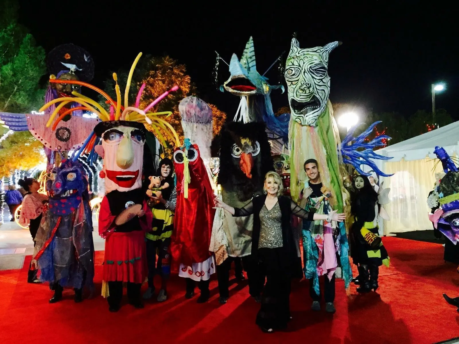 Linda Smith, a motivational speaker, stands smiling on a red carpet surrounded by colorful, oversized puppets and creative performers at a vibrant charity event, highlighting her work in nonprofit fundraising and advocacy.| Linda’s Life – Linda Smith