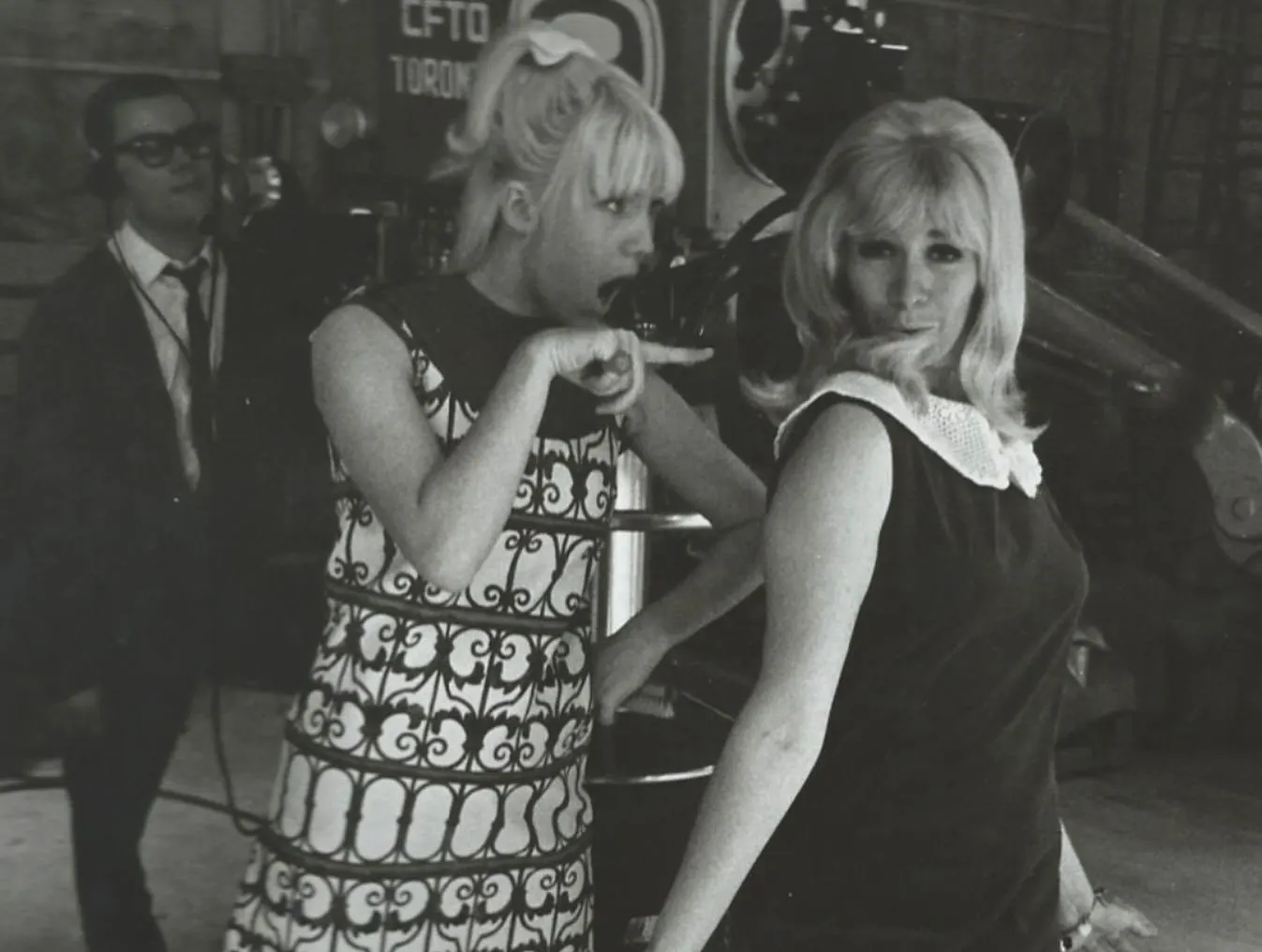 Two women in 1960s attire are in a TV studio, one pointing and speaking animatedly. A man with glasses stands behind them with equipment. This…| Linda’s Life – Linda Smith