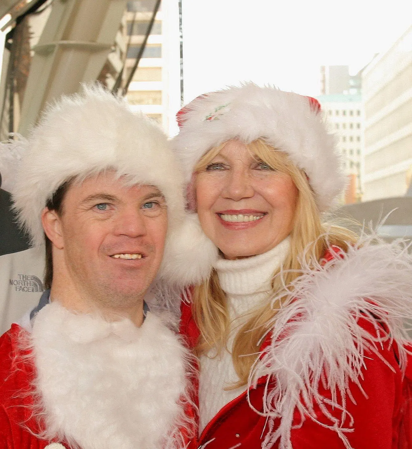 A woman and a man, both in festive Santa hats and red attire, smile warmly at a charity event focused on Down syndrome awareness, embodying the spirit of nonprofit fundraising and advocacy.| Linda’s Life – Linda Smith