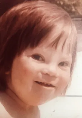 A young child with a joyful expression, light brown hair, and a sunny background, representing the focus on Down syndrome awareness central to Linda Smith’s advocacy and motivational speaking efforts.| Linda’s Life – Linda Smith
